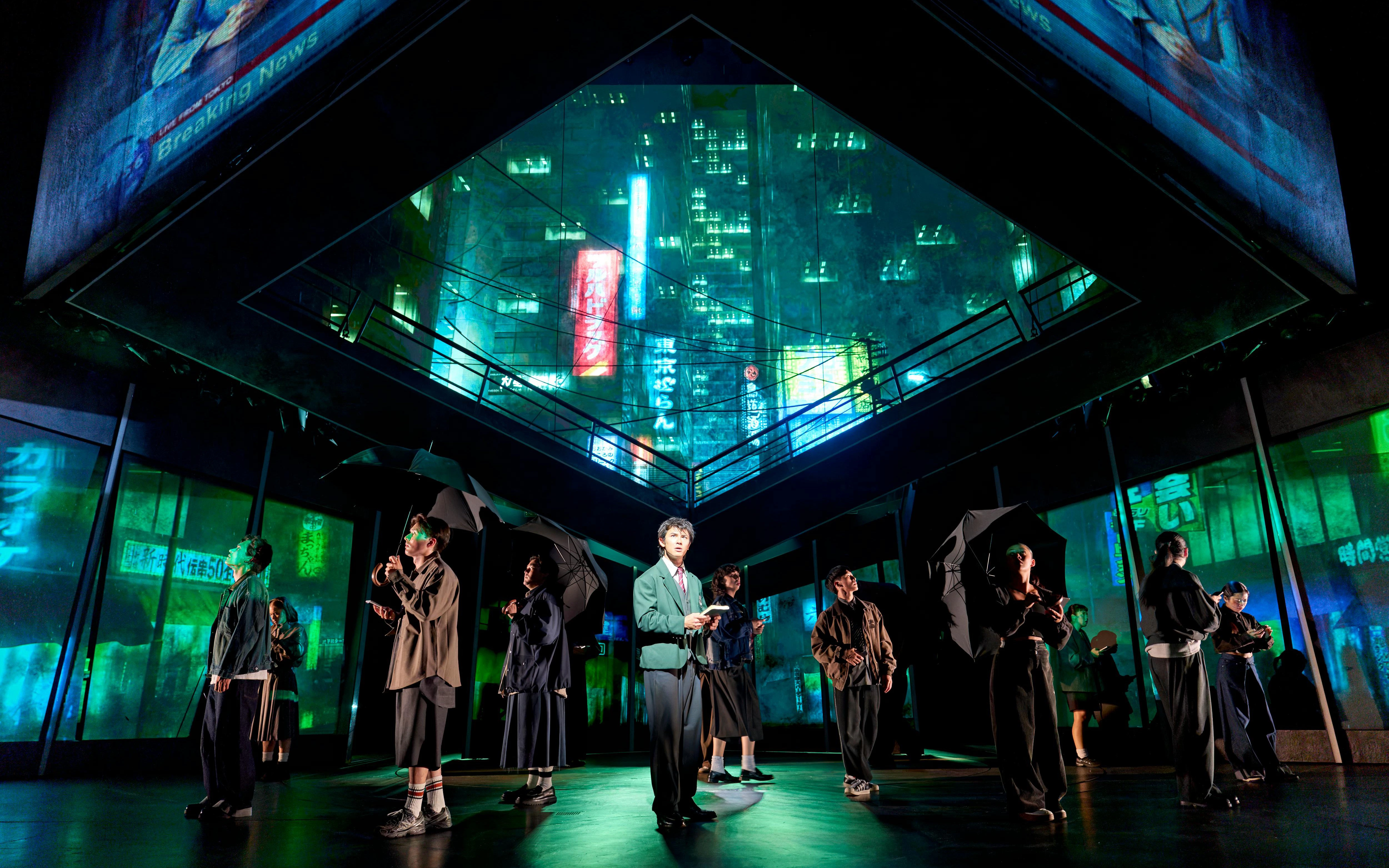 Stage performance of Death Note with actors holding umbrellas under neon cityscape.