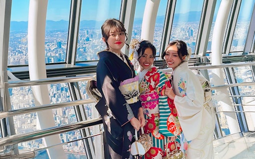 Women in kimonos at Tokyo Skytree observation deck with city view.