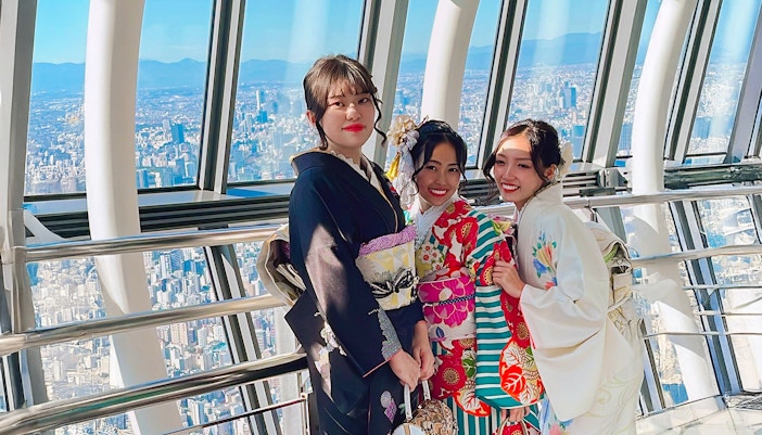 Women in kimonos at Tokyo Skytree observation deck with city view.