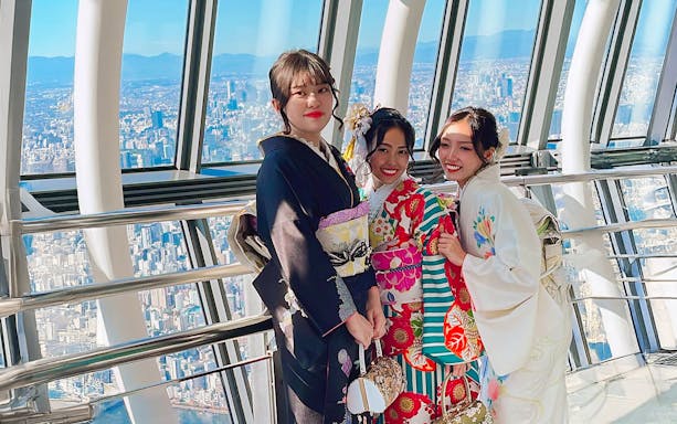 Women in kimonos at Tokyo Skytree observation deck with city view.