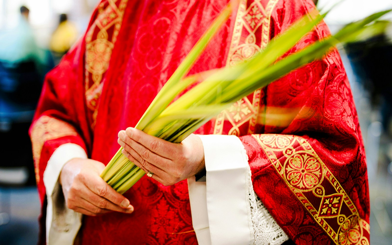 Priest holding palm leaves during Palm Sunday procession.