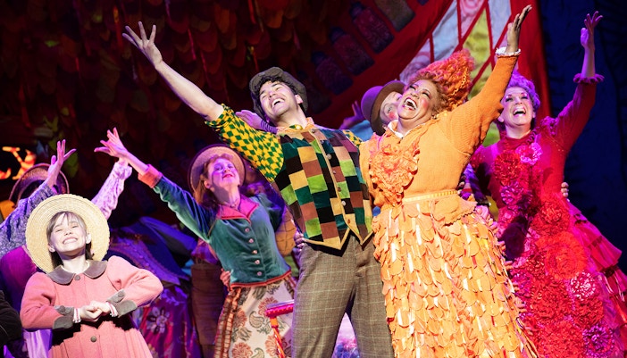 Performers in colorful costumes on stage during a Mary Poppins musical scene.