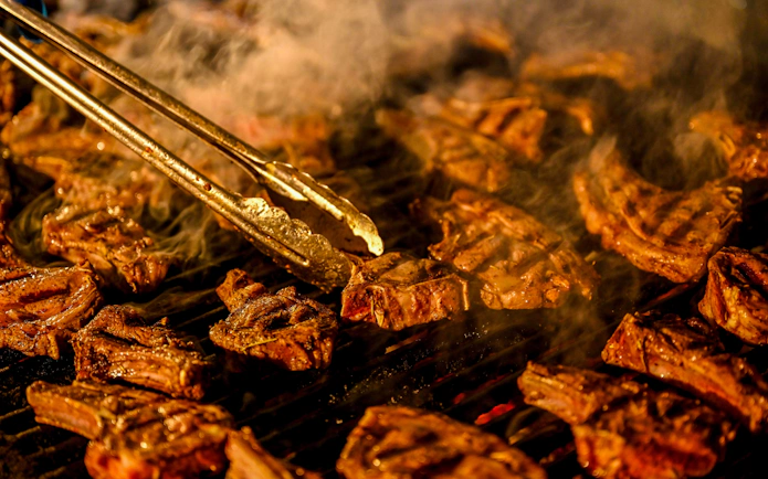 BBQ lamb chops grilling during desert safari experience.