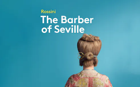 Back view of a person with styled hair and scissors, promoting "The Barber of Seville.