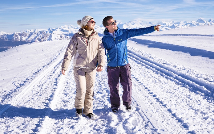 Couple walking on snowy path at Glacier 3000, Montreux, with scenic mountain views.