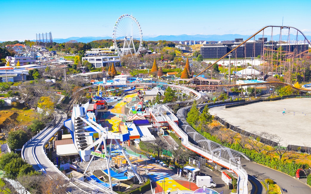 Yomiuriland amusement park with roller coasters and Ferris wheel in Tokyo, Japan.