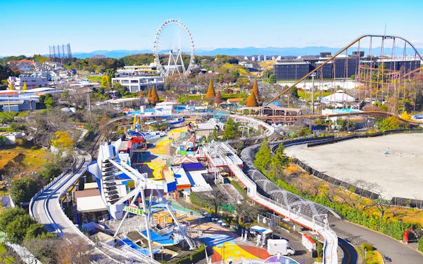 Yomiuriland amusement park with roller coasters and Ferris wheel in Tokyo, Japan.