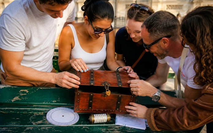 Group opening a treasure chest during a Paris treasure hunt tour from the Panthéon to the Louvre.