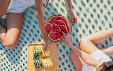 Guests enjoying fresh watermelon and pineapple on Heraklion catamaran cruise.
