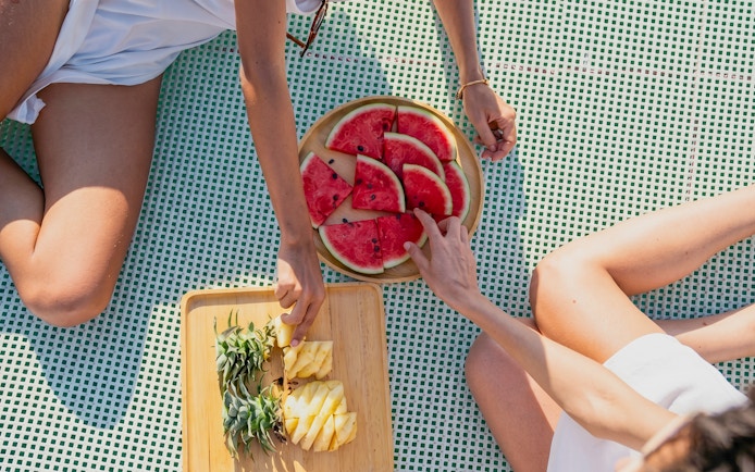 Guests enjoying fresh watermelon and pineapple on Heraklion catamaran cruise.