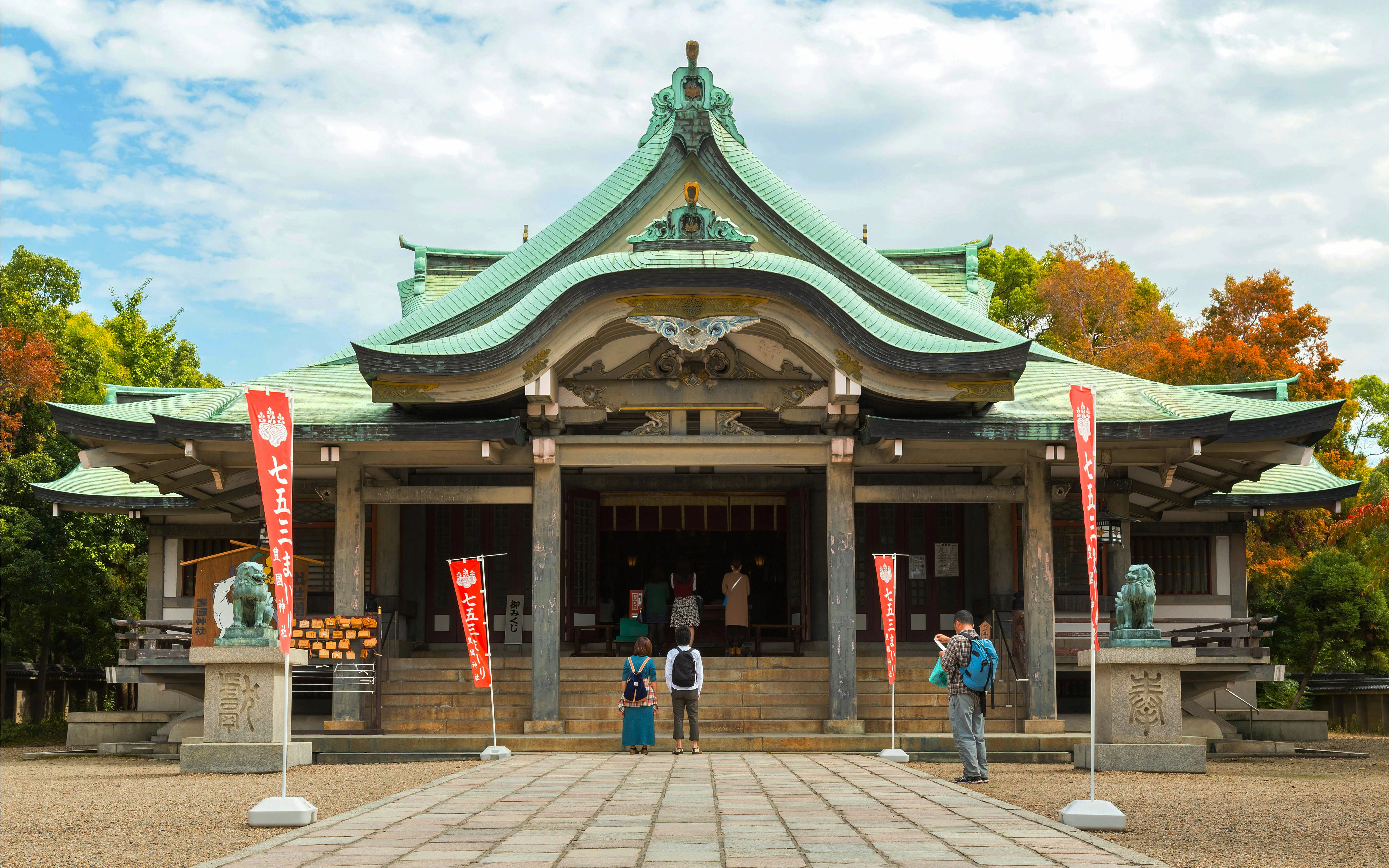 Hokoku Shrine entrance in Osaka with visitors and traditional architecture.
