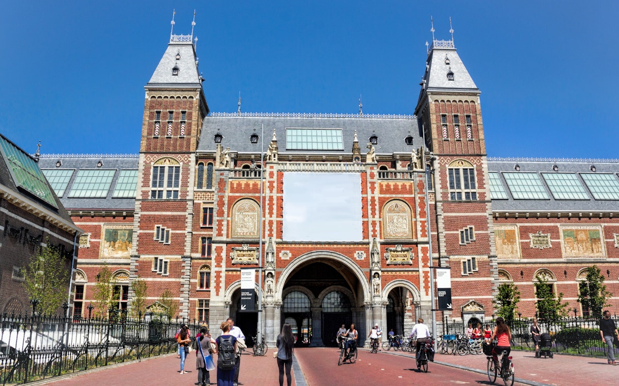 Rijksmuseum entrance with cyclists and visitors in Amsterdam.