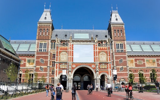 Rijksmuseum entrance with cyclists and visitors in Amsterdam.
