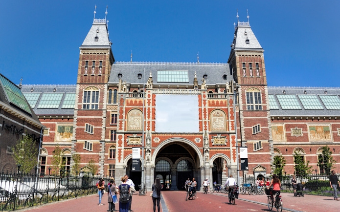 Rijksmuseum entrance with cyclists and visitors in Amsterdam.