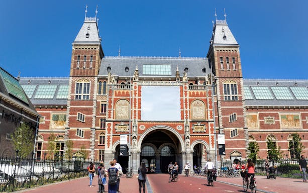 Rijksmuseum entrance with cyclists and visitors in Amsterdam.