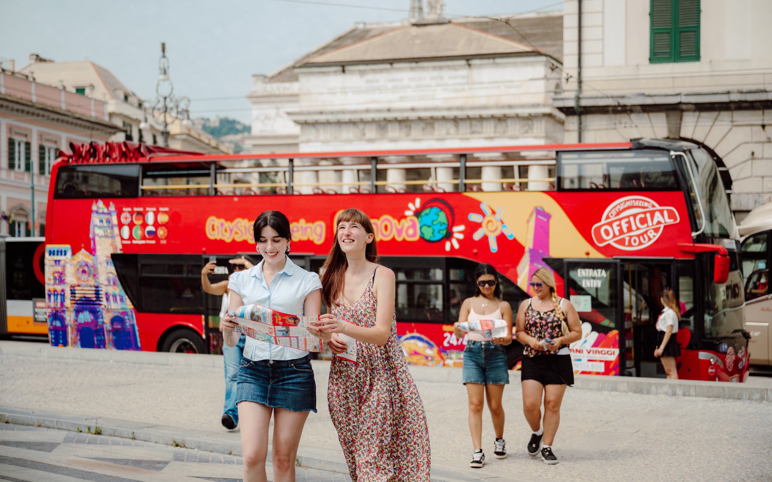 Tourists with maps near a Genova city sightseeing bus.