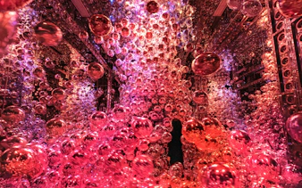 Immersive light and shadow art installation with red spheres at teamLab Biovortex Kyoto.