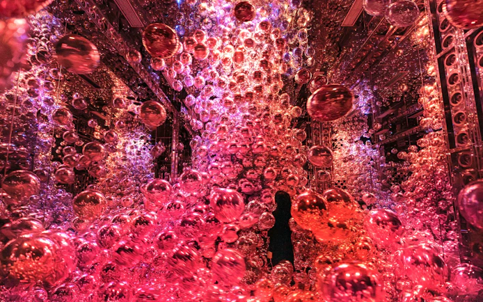 Immersive light and shadow art installation with red spheres at teamLab Biovortex Kyoto.
