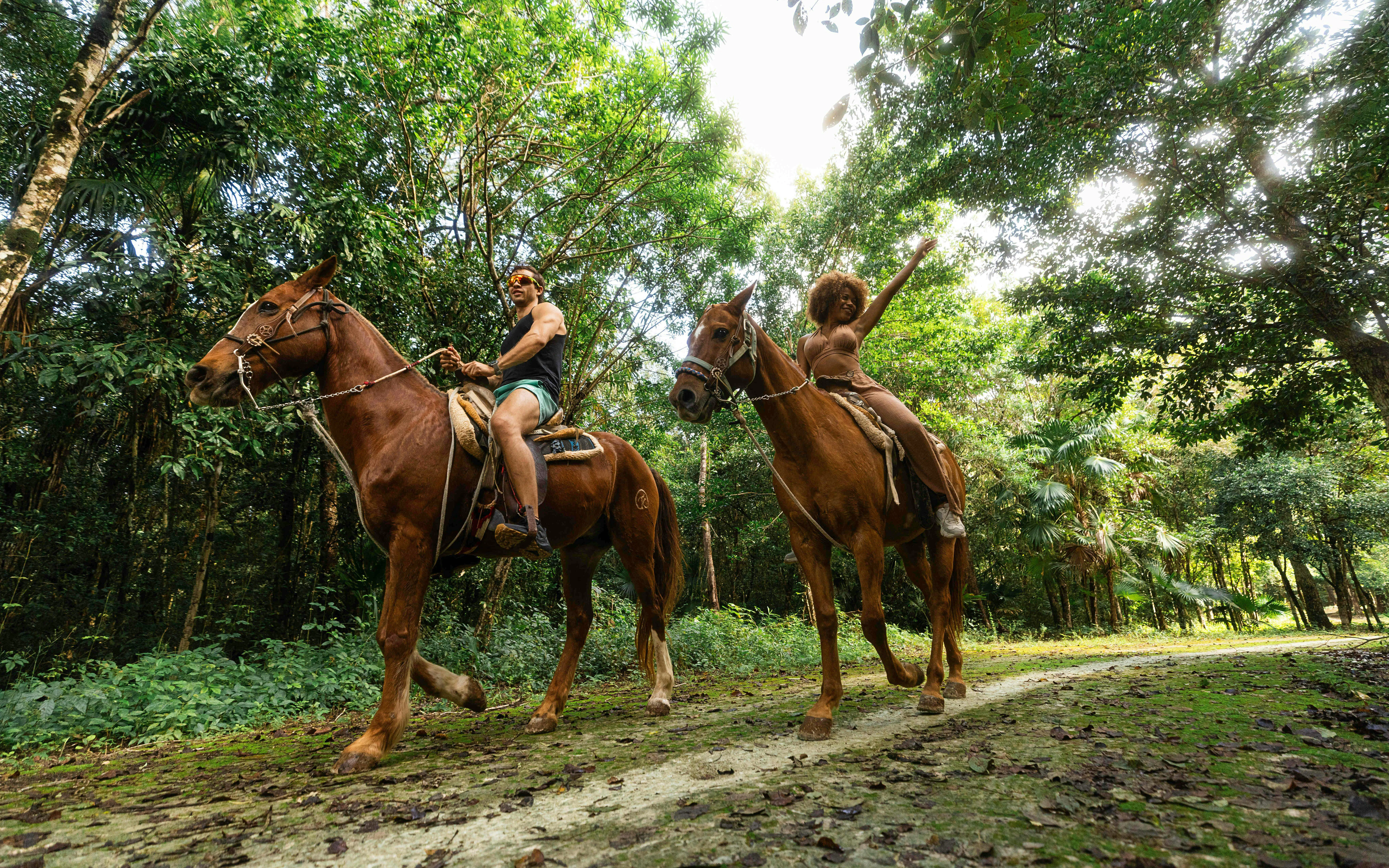 Horseback riding through lush forest at Cancun Extreme Adventuring Park.