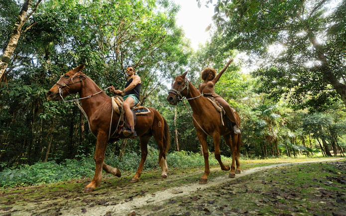 Horseback riding through lush forest at Cancun Extreme Adventuring Park.