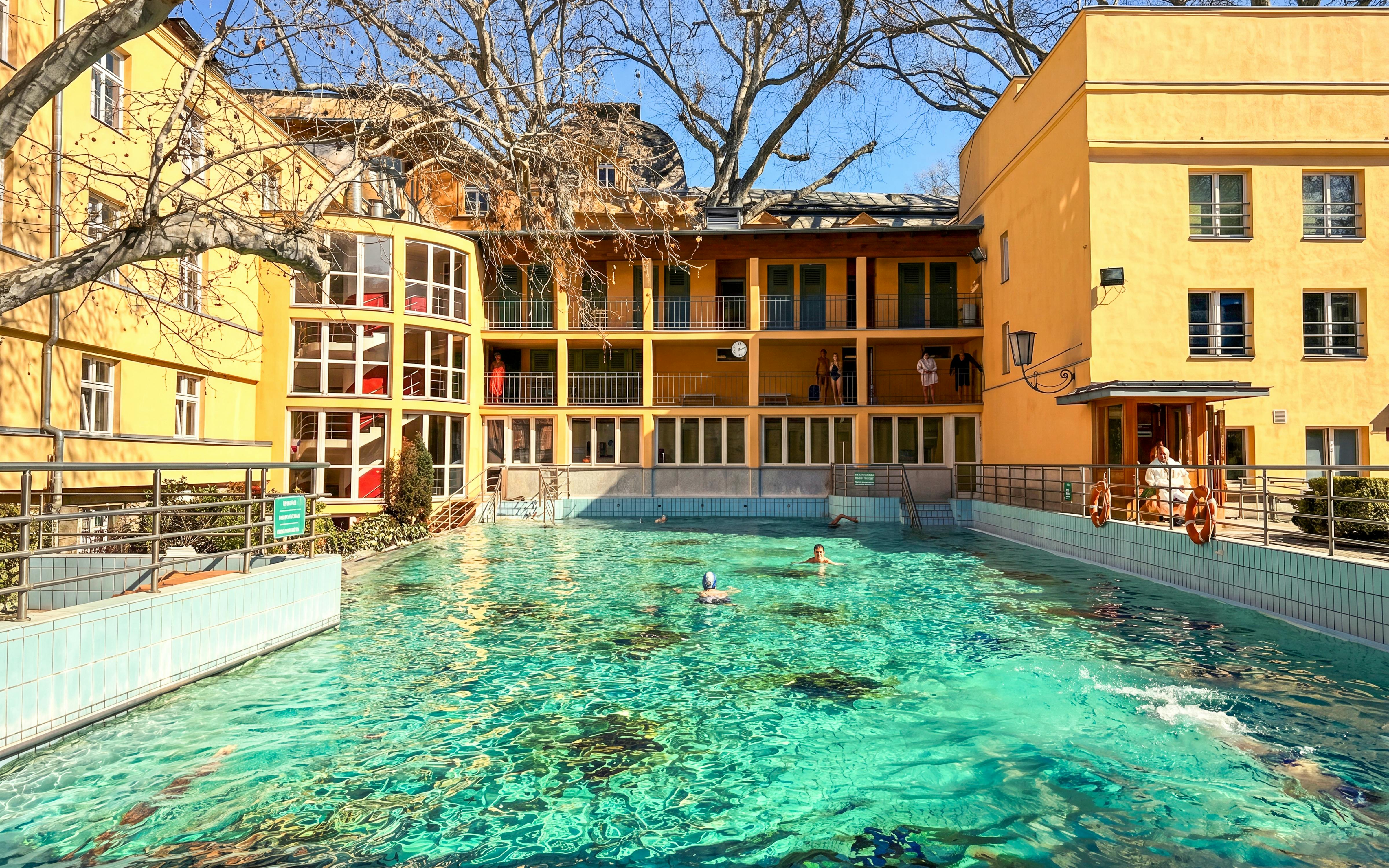 Outdoor thermal pool at Lukács Baths, Budapest, with swimmers enjoying the water.