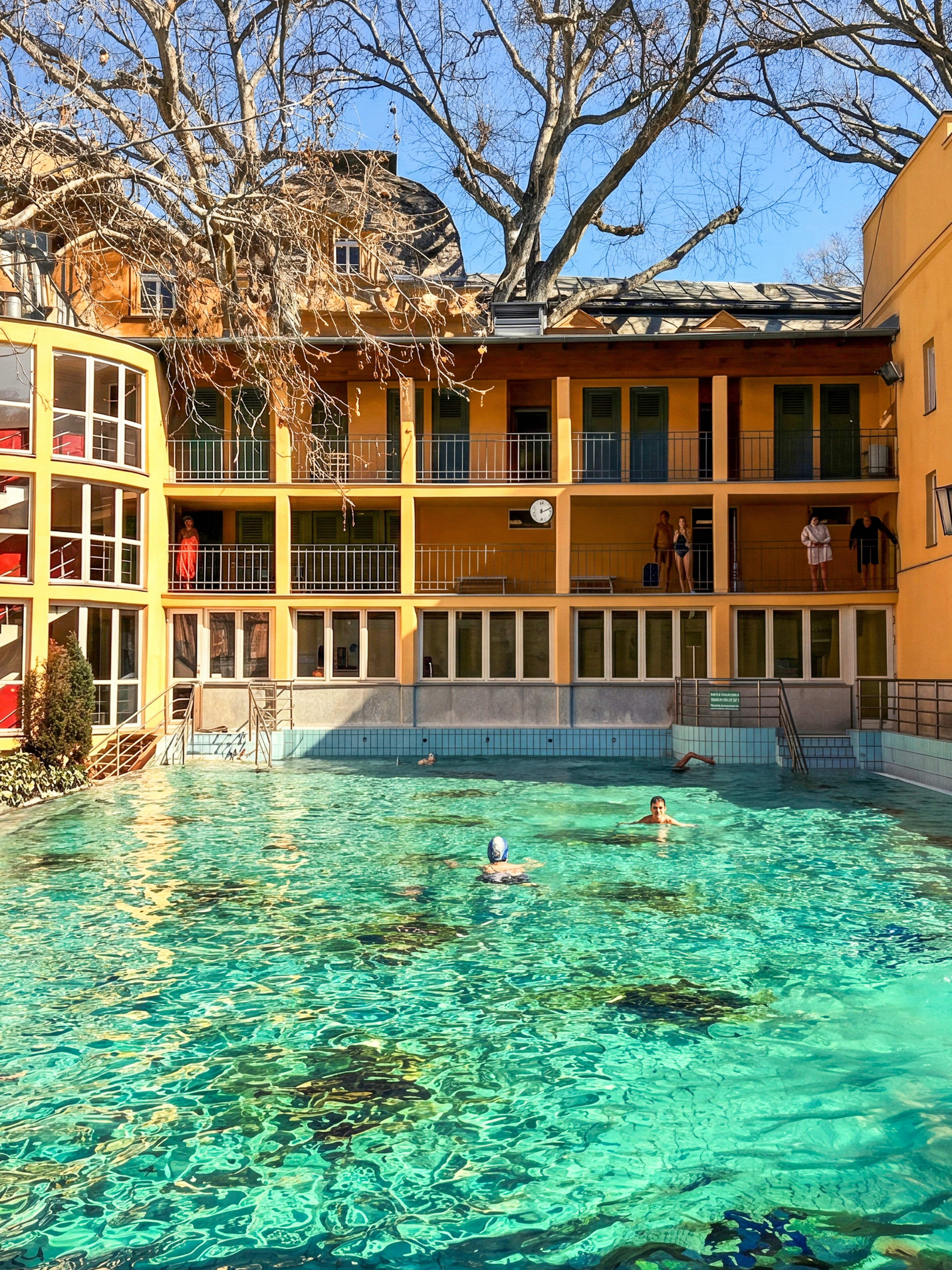 Outdoor thermal pool at Lukács Baths, Budapest, with swimmers enjoying the water.