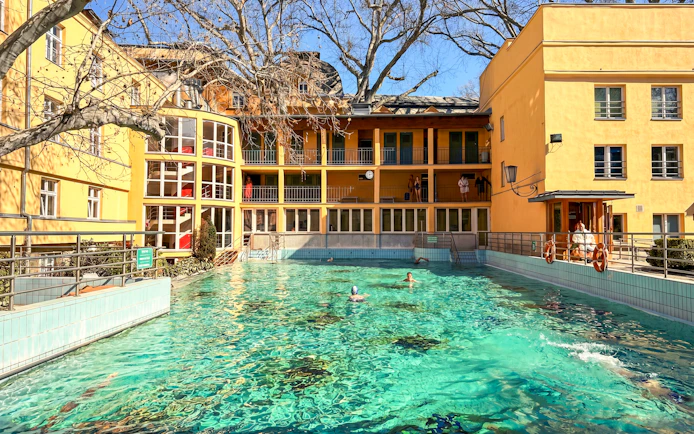 Outdoor thermal pool at Lukács Baths, Budapest, with swimmers enjoying the water.