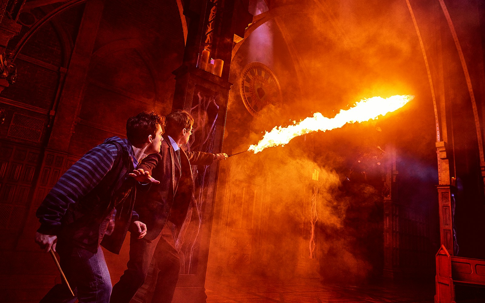 Characters casting a spell with fire in "Harry Potter and the Cursed Child" stage scene.