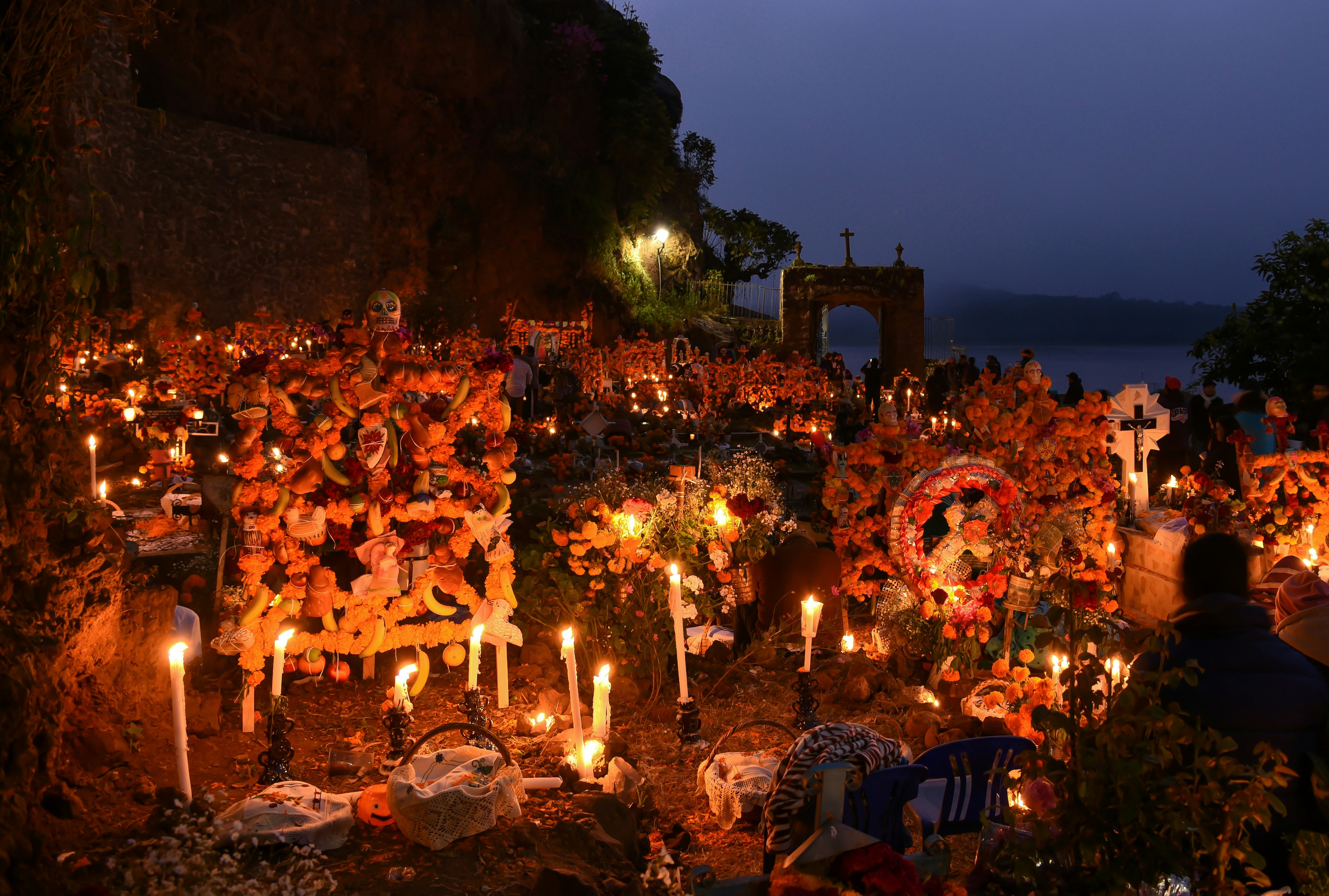 Cemetery adorned with marigolds and candles during Day of the Dead celebration.