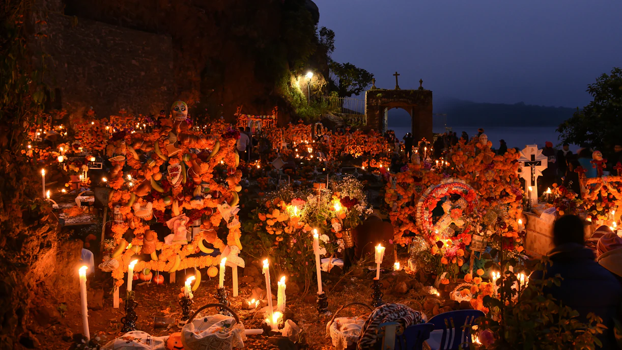 Cemetery adorned with marigolds and candles during Day of the Dead celebration.