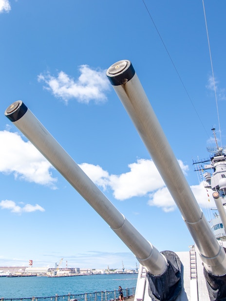 Battleship Missouri Memorial's large naval guns against a clear sky in Pearl Harbor.