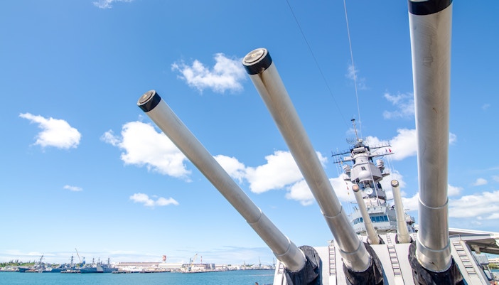 Battleship Missouri Memorial's large naval guns against a clear sky in Pearl Harbor.