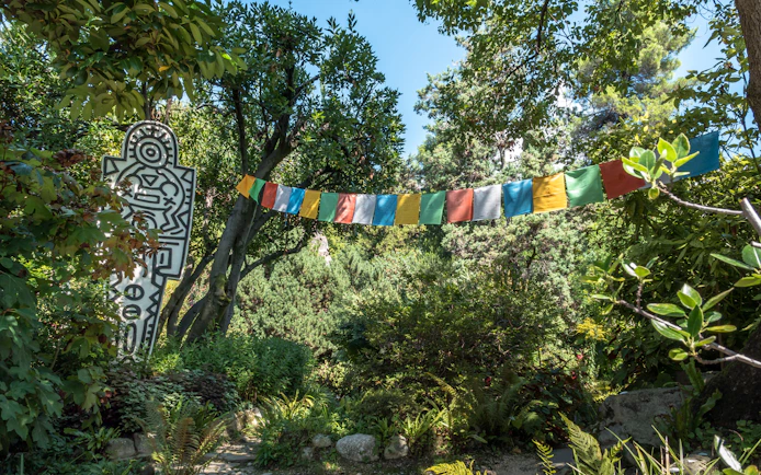 Colorful flags and abstract sculpture in lush ANIMA Garden, Marrakech.