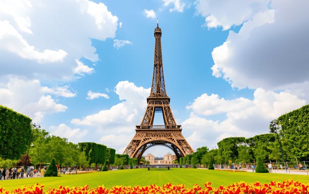 Eiffel Tower in Paris with gardens and blue sky.