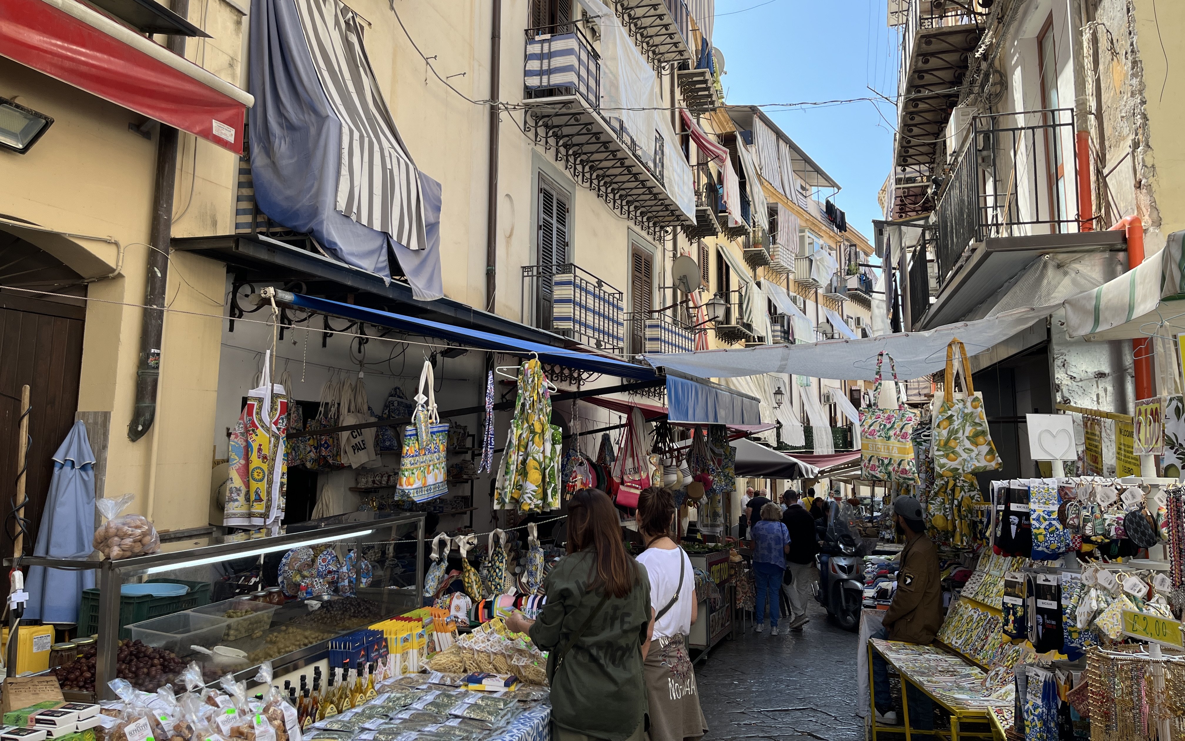 Palermo street market with stalls selling local goods and tourists exploring.