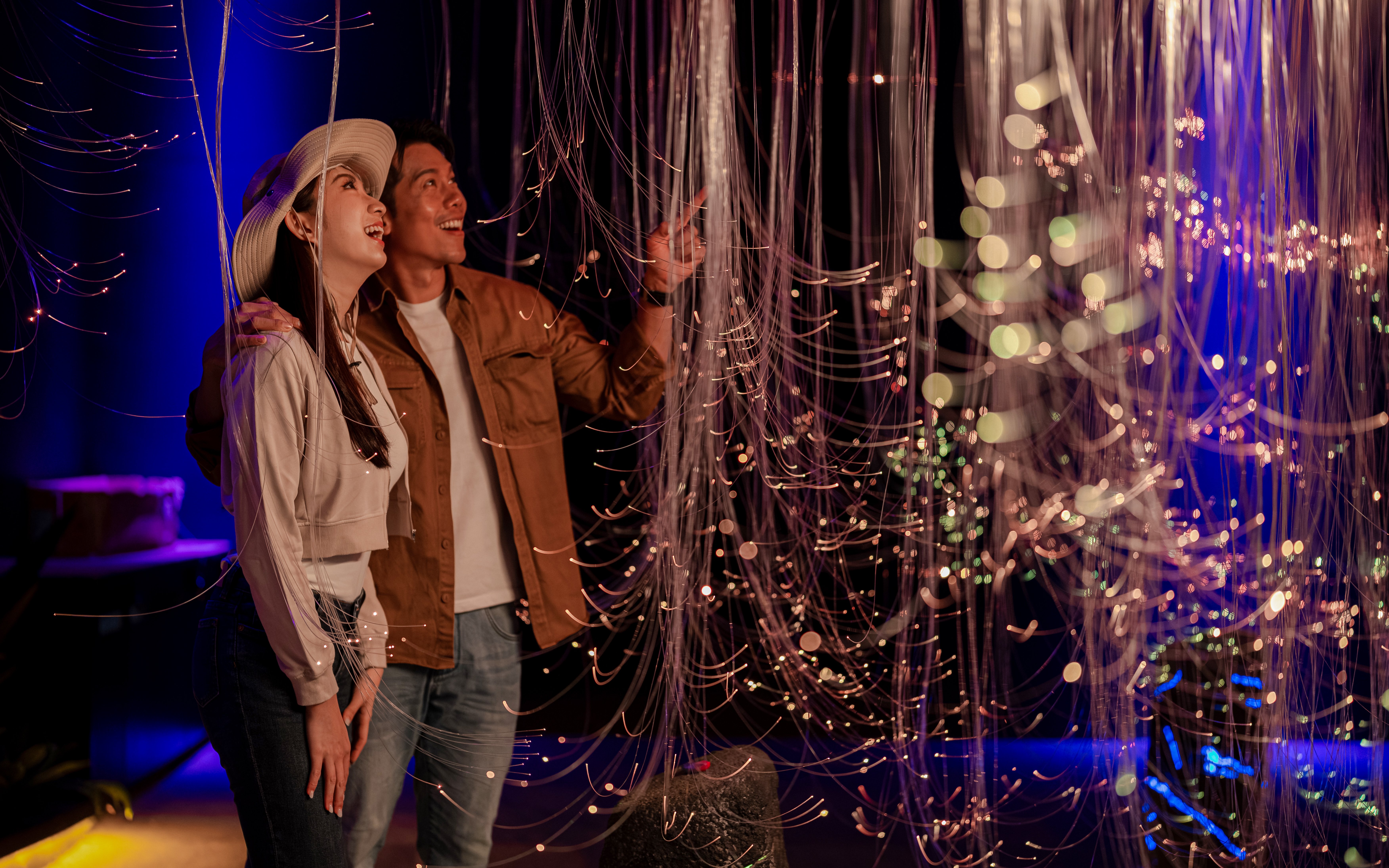 Couple admiring light installation at Enchanted Forest exhibit.