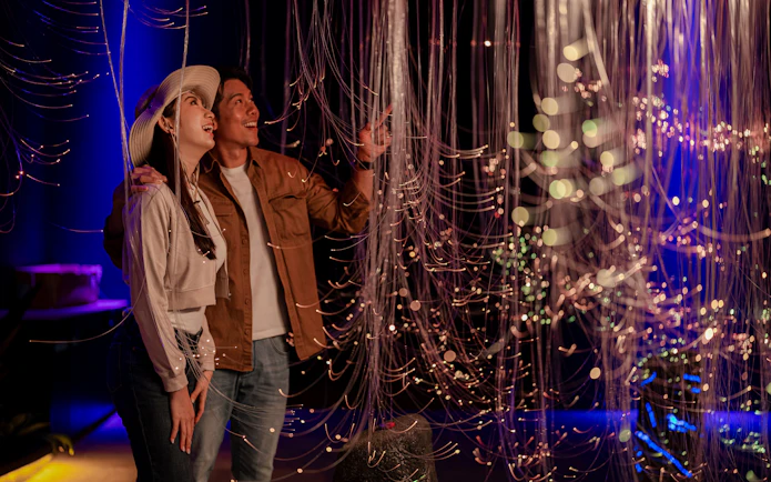 Couple admiring light installation at Enchanted Forest exhibit.
