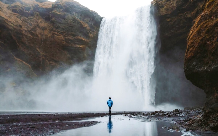 Guests standing near Skogafoss waterfall in Iceland.