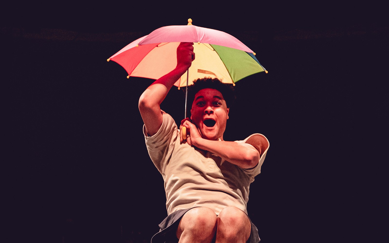 Performer with colorful umbrella in Tom, Dick and Harry show.