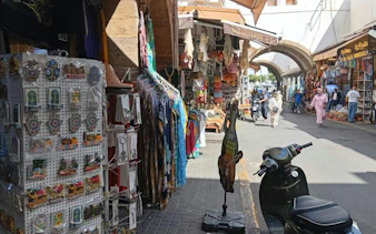 Bazaars in Marrakech with colorful clothing and souvenirs, part of Casablanca day trip.