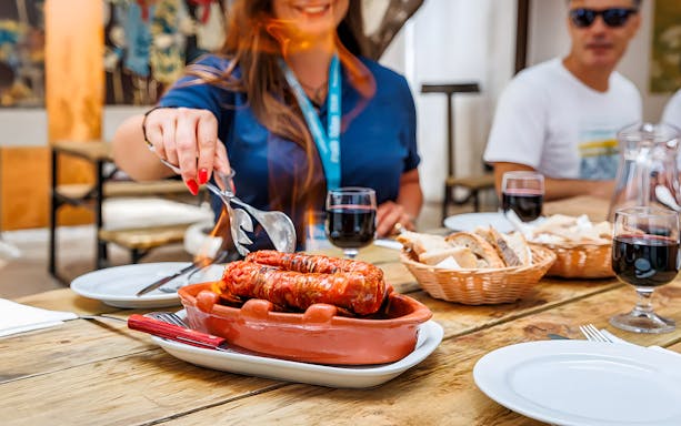 Tourist sampling Chorizo during Lisbon Food Walk in Baixa.