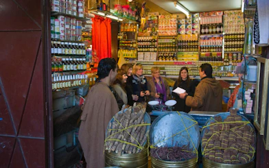 Group exploring spice shop in Fes Old Medina souks, Morocco.