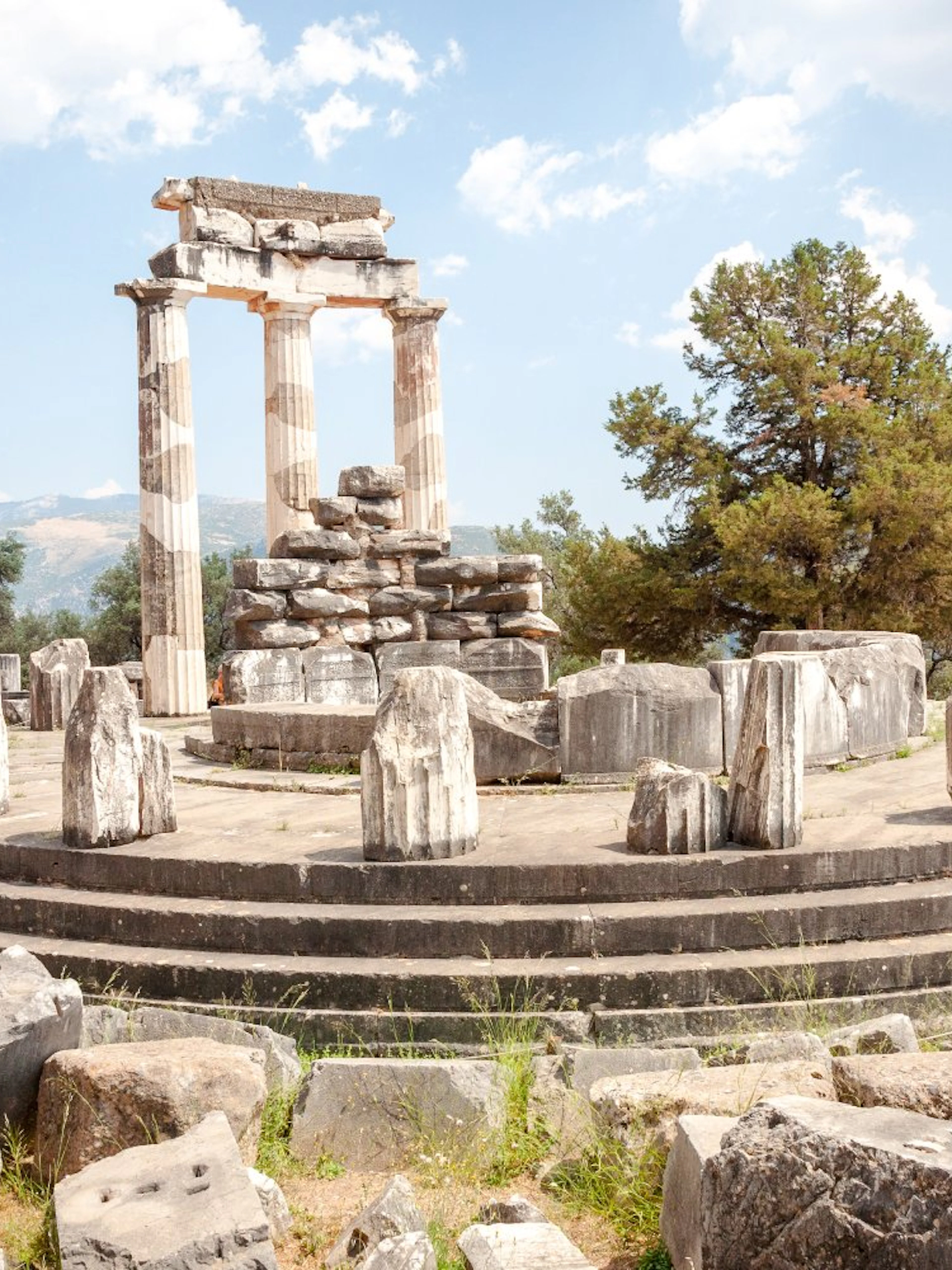 Ancient ruins of the Tholos of Delphi with surrounding landscape in Greece.