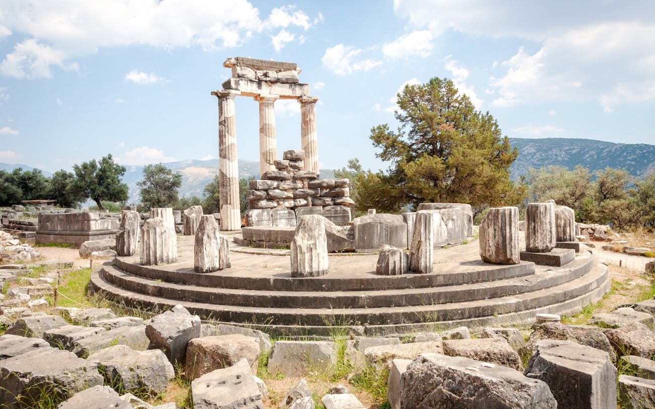 Ancient ruins of the Tholos of Delphi with surrounding landscape in Greece.