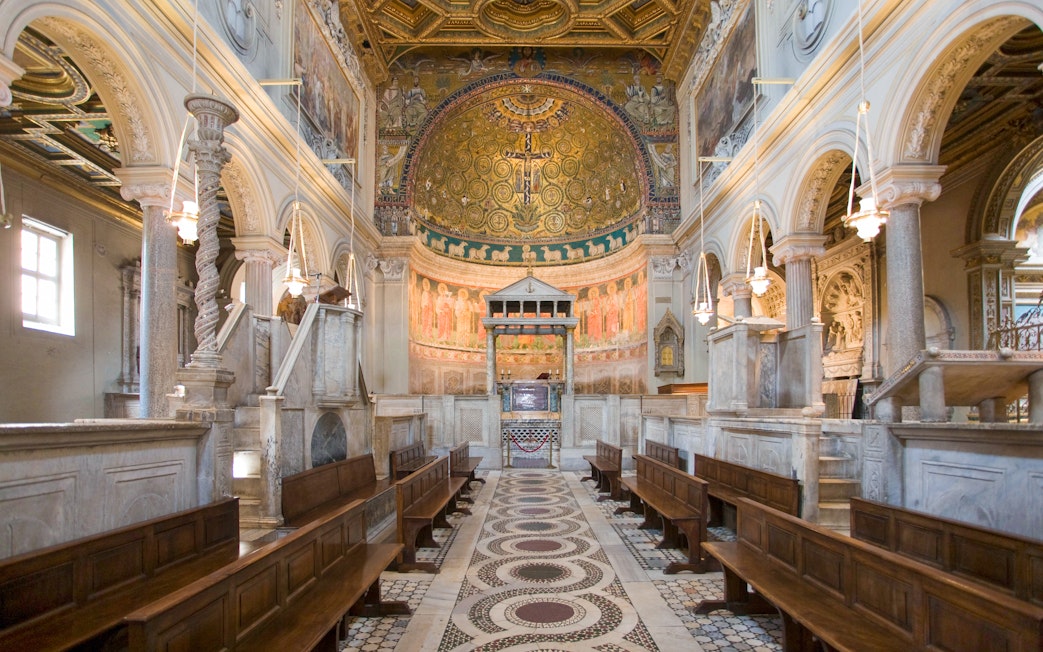 Interior of San Clemente Basilica in Rome with ornate frescoes and marble columns.