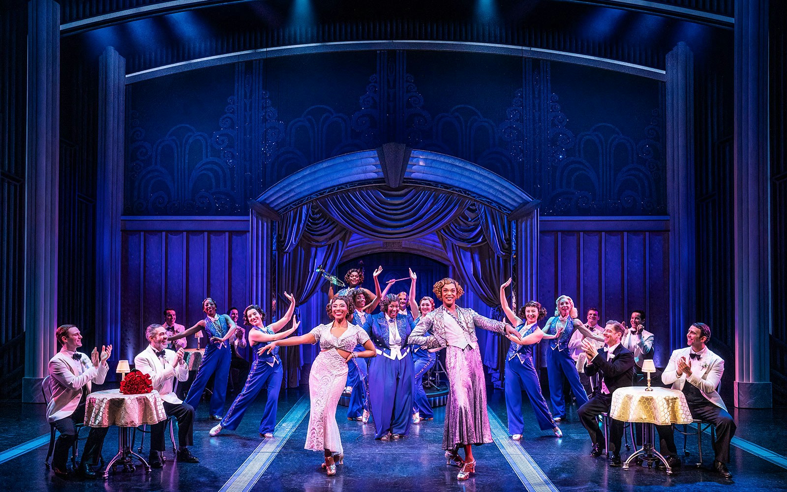 Stage performance of "Some Like it Hot" musical with dancers in elegant costumes.