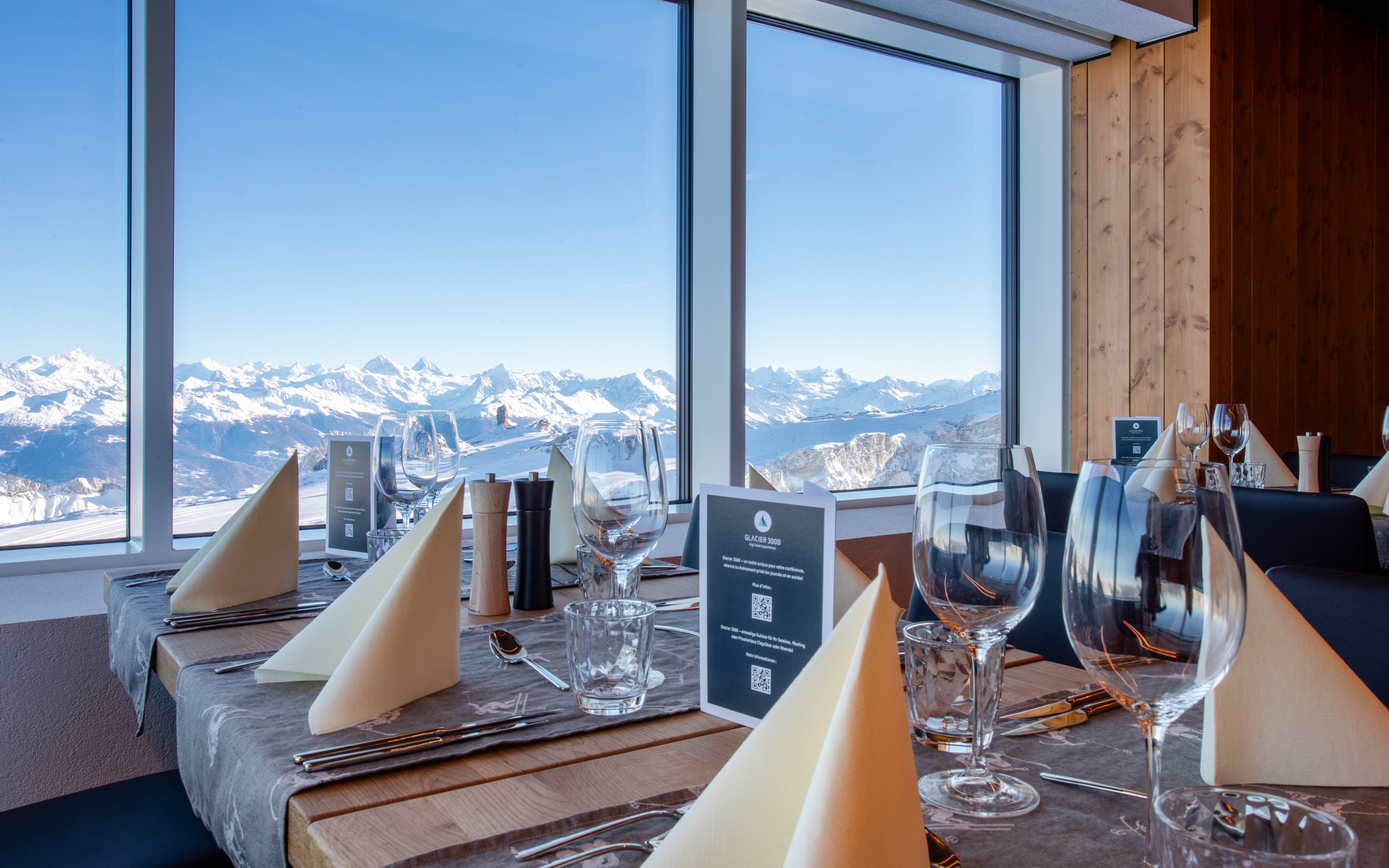 Restaurant table with view of snow-covered glaciers at Glacier 3000, Switzerland.