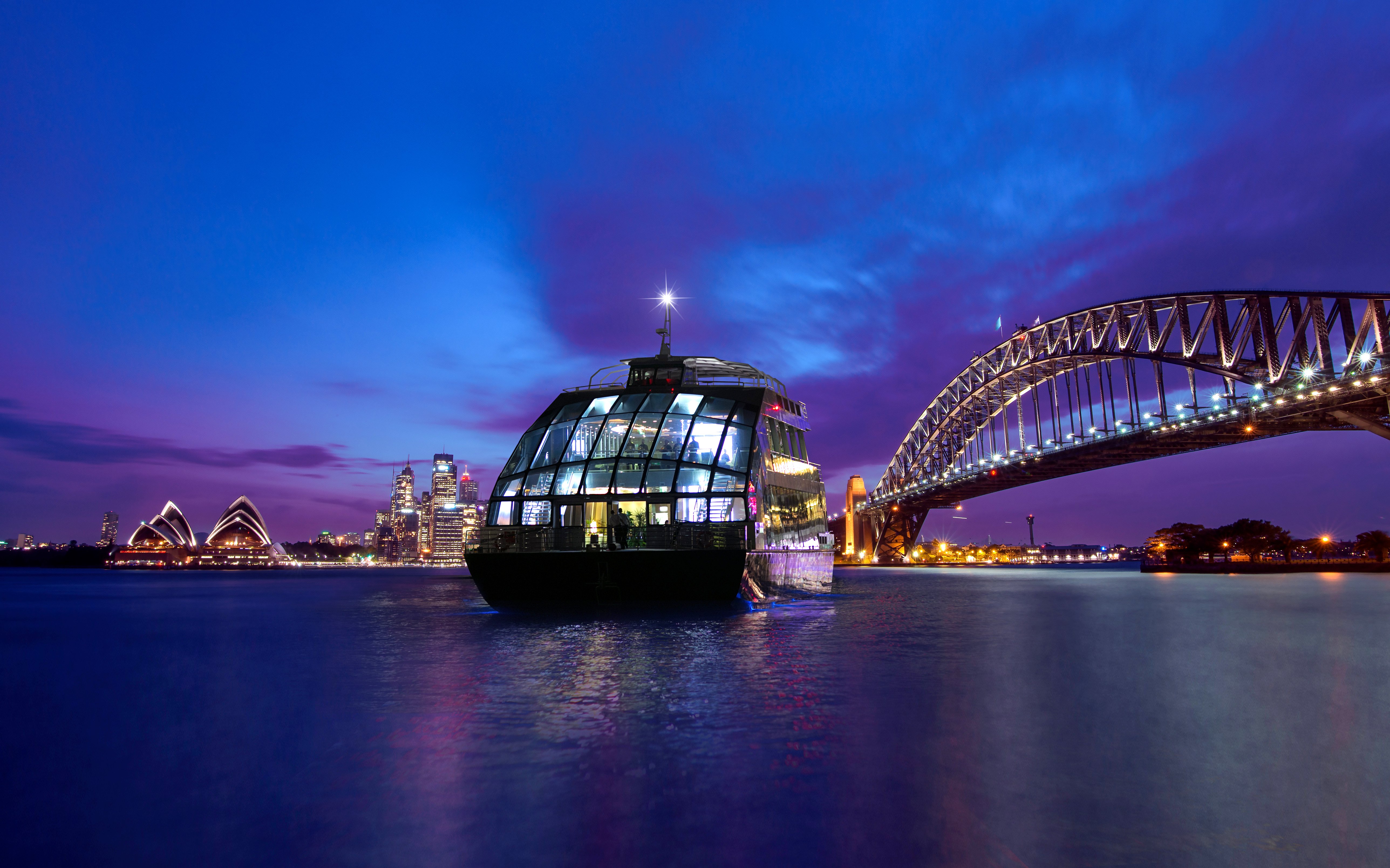 Glass boat on Sydney Harbour with views of the Opera House and Harbour Bridge at dusk.