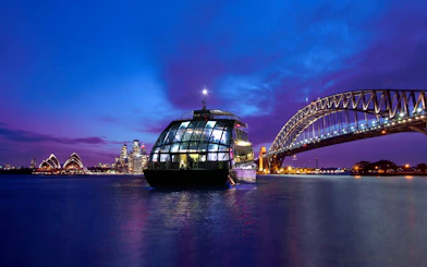 Glass boat on Sydney Harbour with views of the Opera House and Harbour Bridge at dusk.