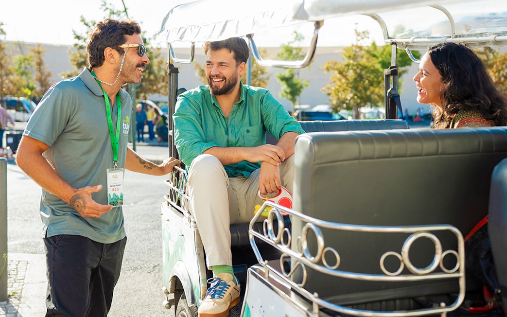 Tourist guide talking with tourists on a tuk tuk in Lisbon.